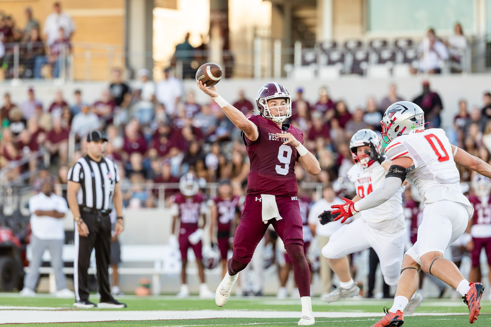 western-colorado-vs-wtamu-jpegJoe-pps-16 | Press Pass Sports Maroon-clad quarterback (No. 9) mid-throw during a college football game with defenders in white pursuing.
