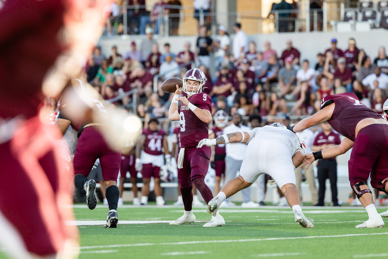western-colorado-vs-wtamu-jpegJoe-pps-17 | Press Pass Sports Quarterback in maroon jersey number 9 throws a pass during a football game with players and a crowd in the background.