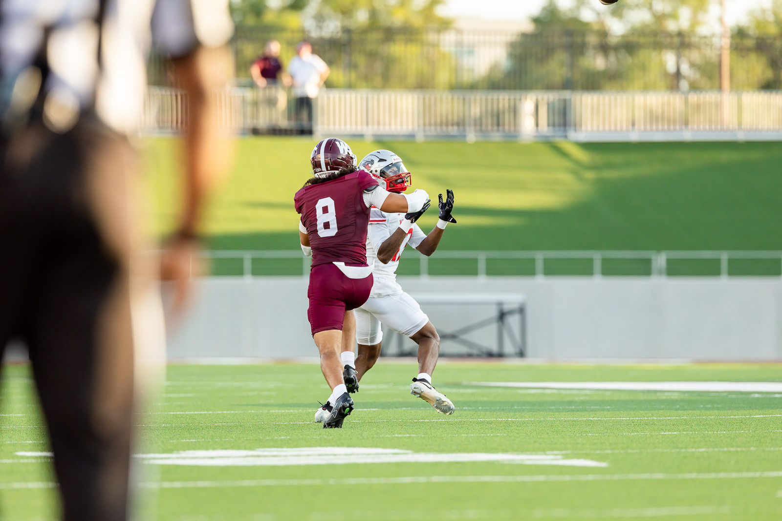 western-colorado-vs-wtamu-jpegJoe-pps-27 | Press Pass Sports Two football players collide for the ball on a sunny green field; maroon jersey (#8) against a white-uniform opponent with spectators in the background.