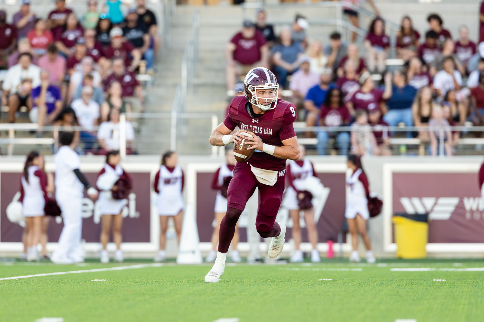 western-colorado-vs-wtamu-jpegJoe-pps-31 | Press Pass Sports Quarterback from West Texas A&M sprints with the football during a game, crowd watching from stands.