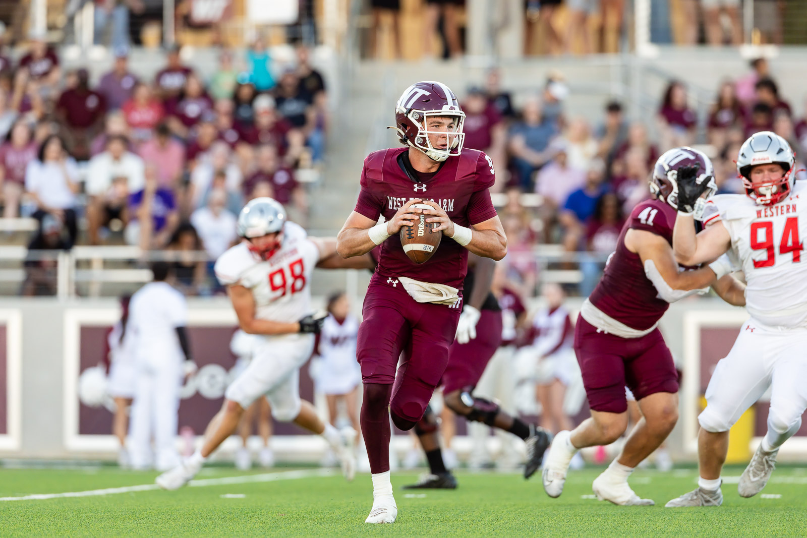 western-colorado-vs-wtamu-jpegJoe-pps-32 | Press Pass Sports Quarterback in maroon uniform runs with the football as defenders close in during a college football game.