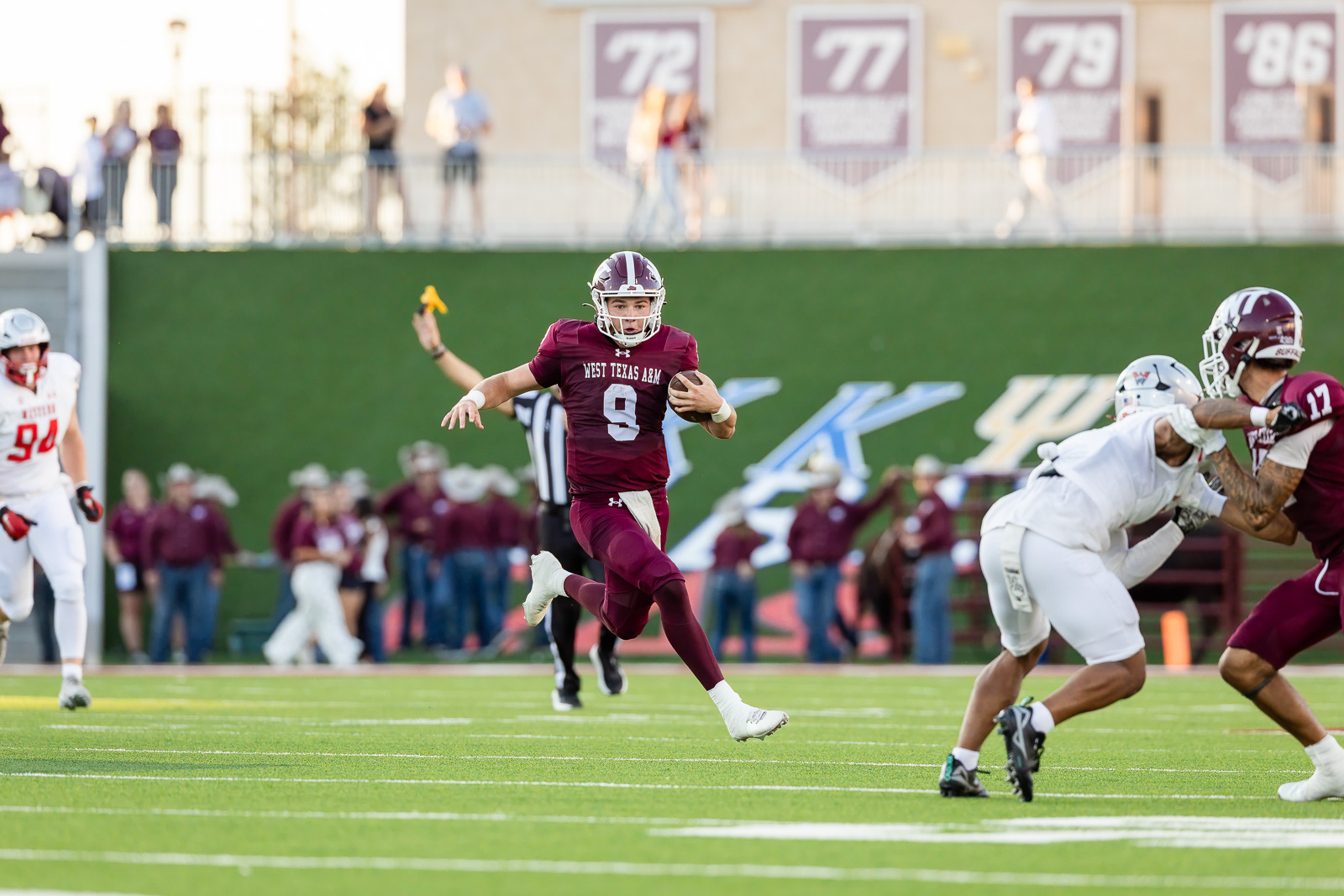 western-colorado-vs-wtamu-jpegJoe-pps-33 | Press Pass Sports Maroon-clad football QB (West Texas A&M #9) sprints down the field with the ball as white-clad defenders close in near the sideline.