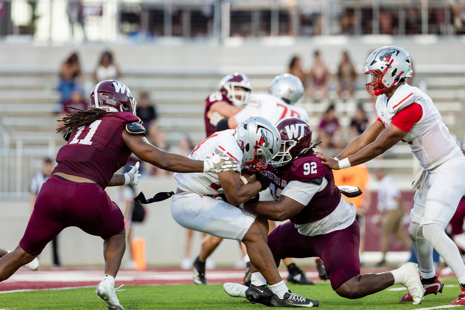 western-colorado-vs-wtamu-jpegJoe-pps-46 | Press Pass Sports Football game action: players in maroon and white collide as a ball carrier is brought down near the line of scrimmage on a green field.