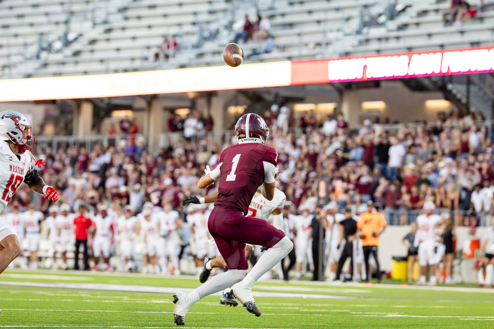 western-colorado-vs-wtamu-jpegJoe-pps-49 | Press Pass Sports Quarterback in maroon (No. 1) throws a football during a college football game as fans cheer in the stands.