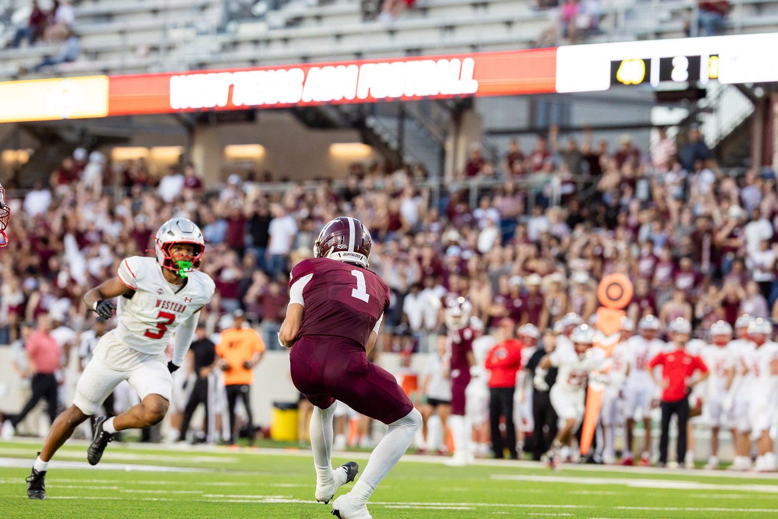 western-colorado-vs-wtamu-jpegJoe-pps-51 | Press Pass Sports Maroon jersey quarterback (#1) runs with the ball as a white-uniform defender pursues, crowded stadium in the background