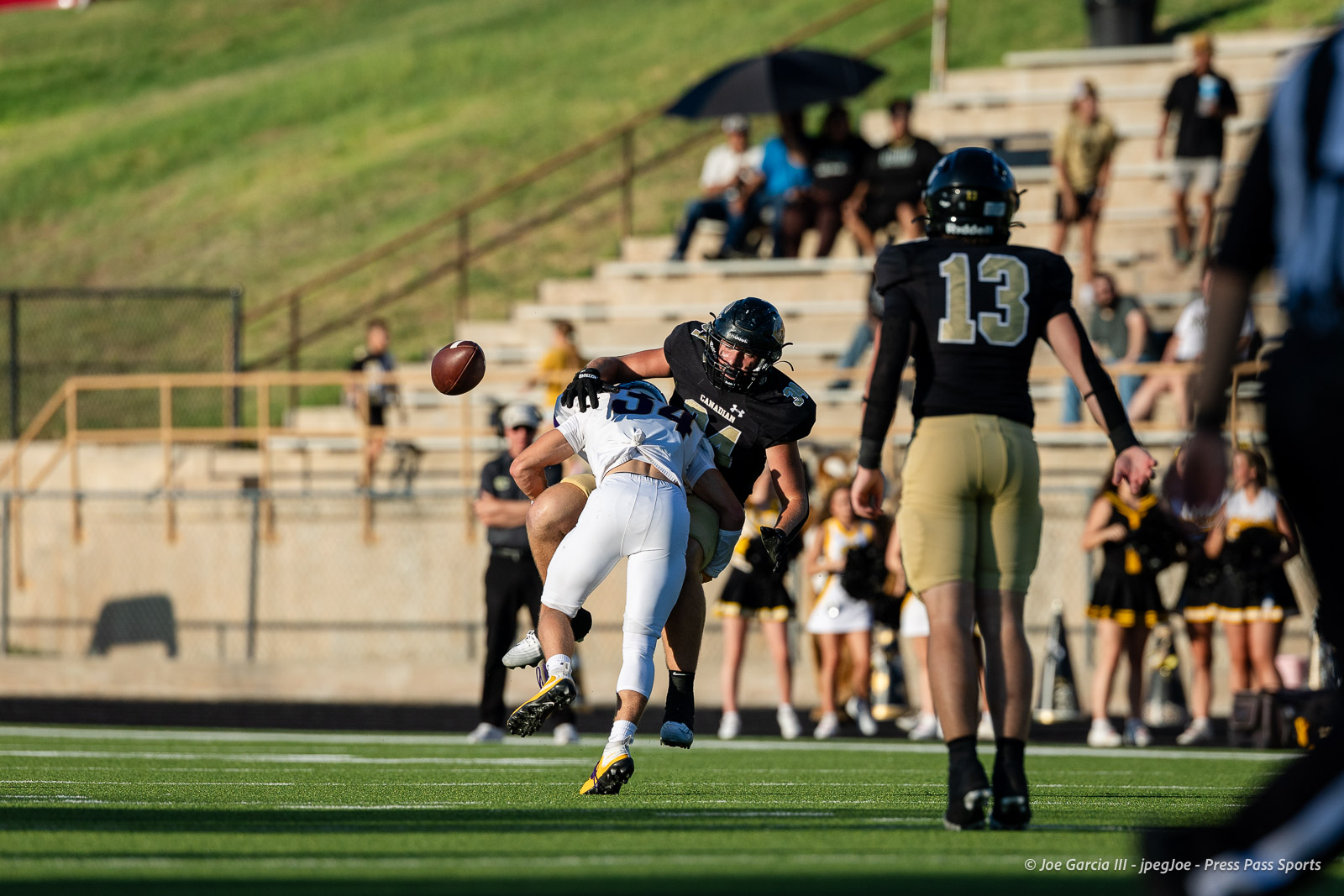 panhnandle-vs-canadian-football-jpegJoe-pps-4 | Press Pass Sports Football players collide as a tackler in black brings down a white-uniform opponent; football sails between them on a sunny day.