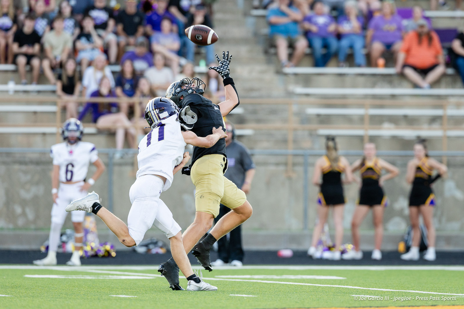 panhnandle-vs-canadian-football-jpegJoe-pps-10 | Press Pass Sports Two football players leap to contest a ball in midair during a game, with a crowd watching from the stands behind them.