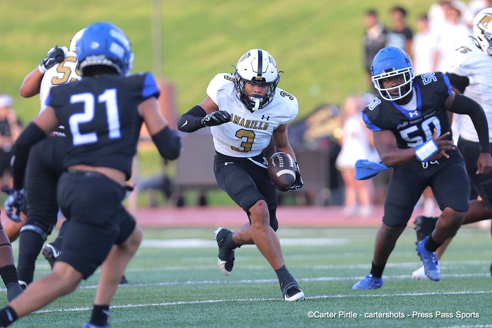 White-jersey football running back #3 carries the ball, darting through defenders on a green turf field.