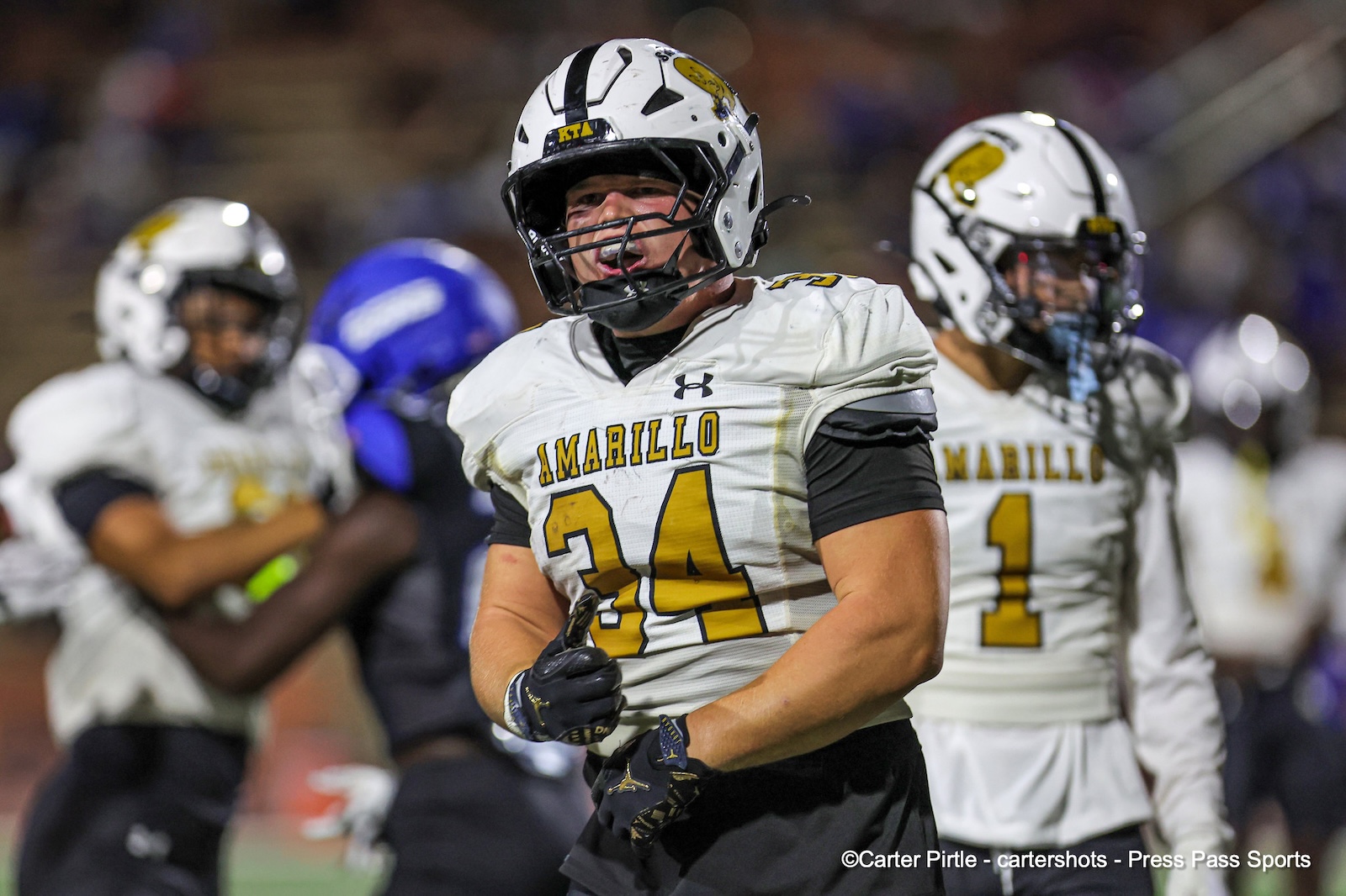 Amarillo football player wearing #34 in a white jersey and helmet runs on the field during a game, gloves on.