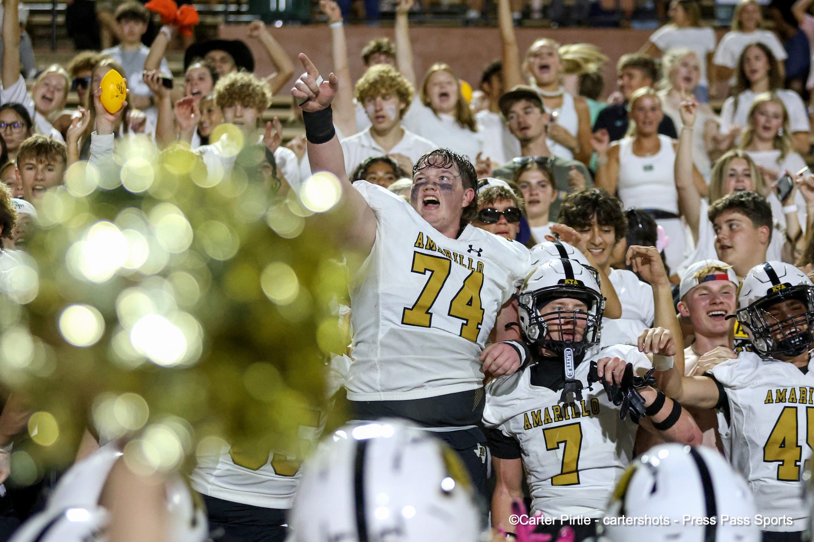 Amarillo football players celebrate in white uniforms as fans cheer in the stands, #74 raises a fist.