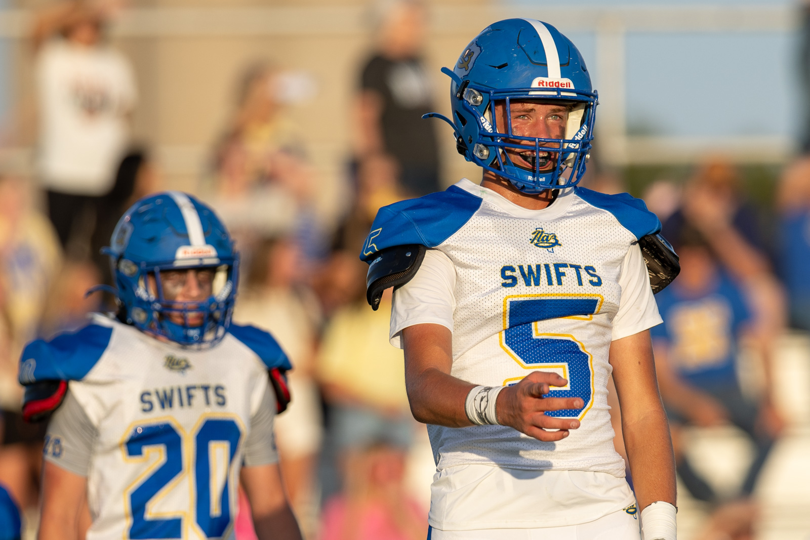 HHS-NHS-FB-39 | Press Pass Sports Two football players in blue and white uniforms on the field, one with the number 5 in the foreground and a teammate in the background.