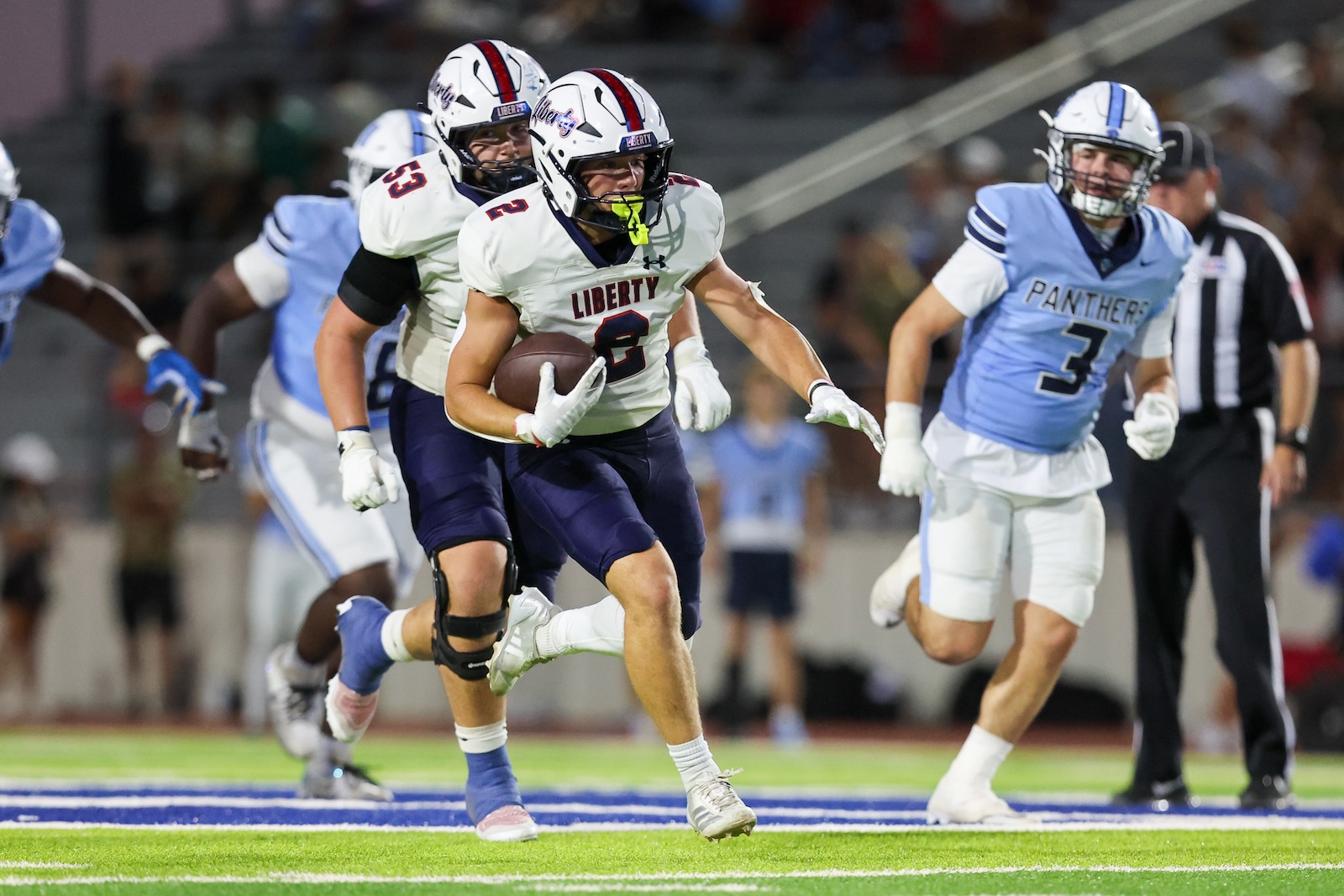 Seabolt Chase-15572 | Press Pass Sports Liberty player (#3) carries the football downfield as defenders from the Panthers pursue during a nighttime football game.