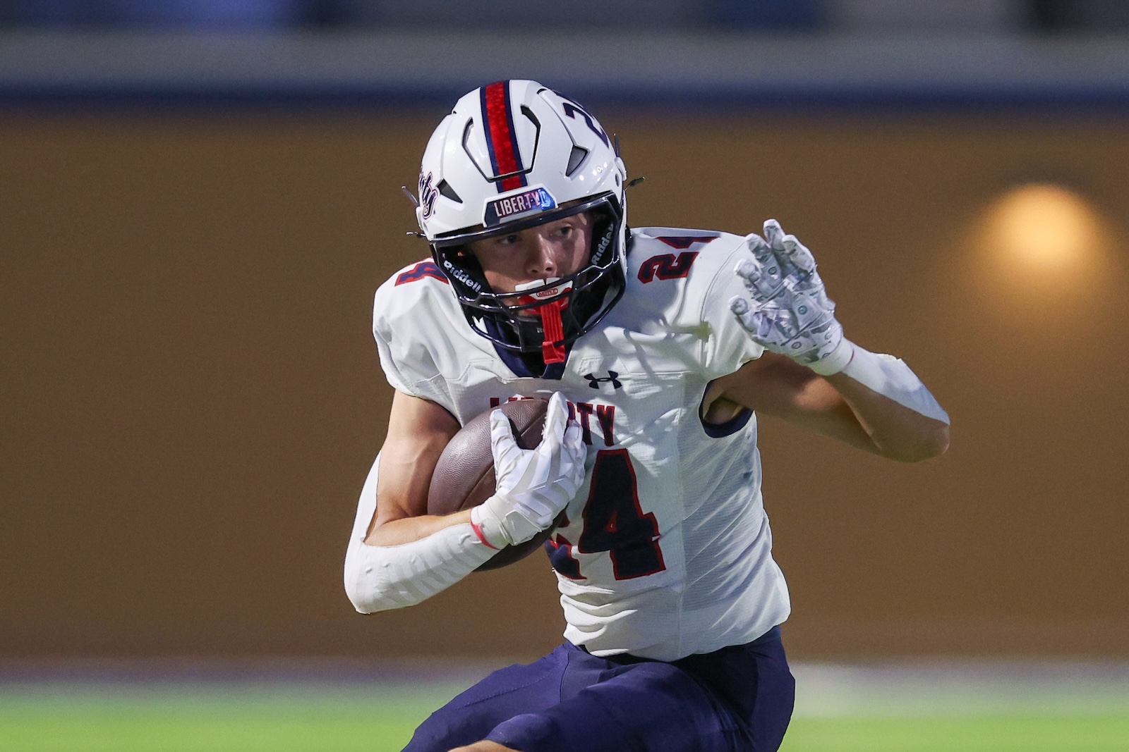 Seabolt Chase-15598 | Press Pass Sports Football player in white jersey holding a ball and running forward, number 4 visible, purple pants, motion shot on field