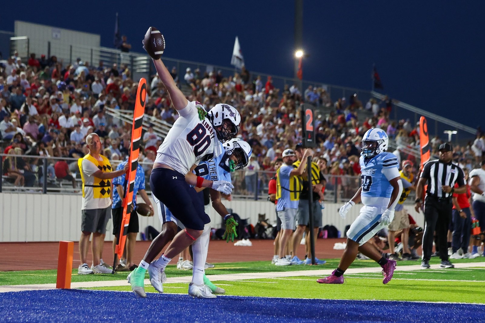 Seabolt Chase-24733 | Press Pass Sports Football player in white jumps to catch a pass at the end zone as a blue defender watches nearby.