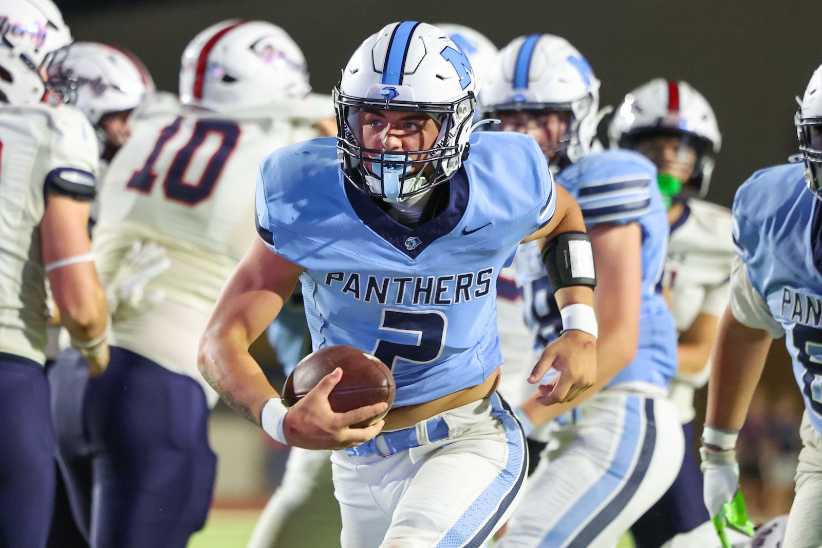 Seabolt Chase-24818 | Press Pass Sports Football player in light blue Panthers uniform running with ball during a rally, defenders in white jerseys behind him.
