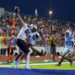 Seabolt Chase-24733 | Press Pass Sports Player in white jersey reaches for a football over the goal line as teammates cheer in a blue end zone while a crowded stands watches at night.