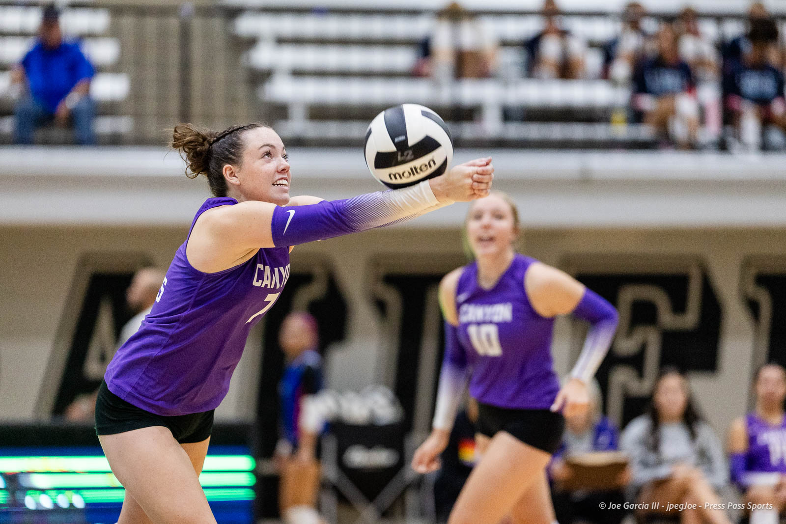 randall-showcase-2026-jpegJoe-pps-4 | Press Pass Sports Female volleyball player in a purple uniform dives forward to receive the ball, another teammate in purple in the background amid spectators.