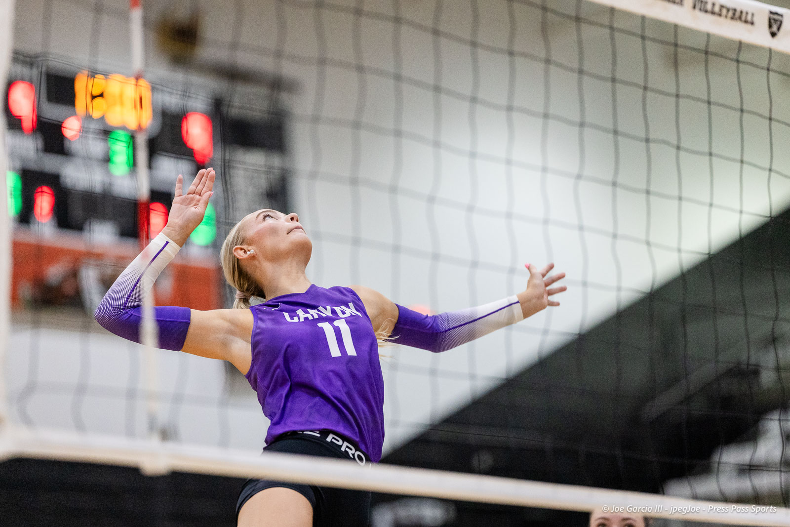 randall-showcase-2026-jpegJoe-pps-12 | Press Pass Sports Female volleyball player in a purple jersey (#11) jumps near the net to spike the ball in an indoor gym setting.
