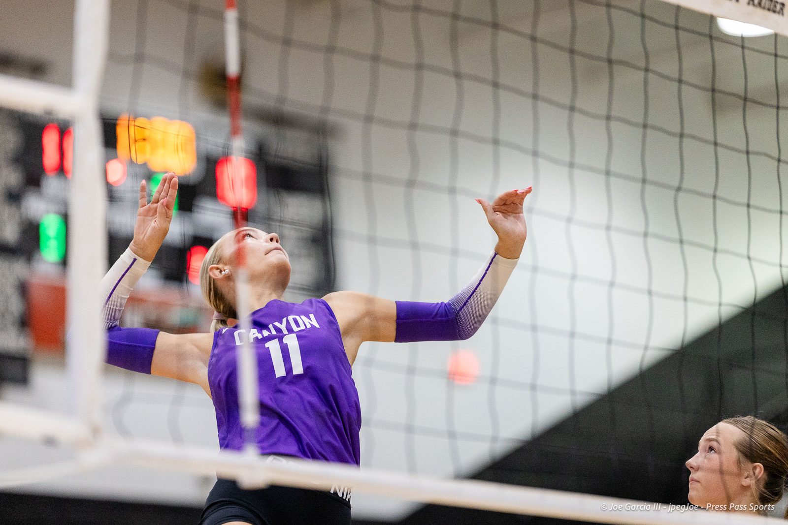 randall-showcase-2026-jpegJoe-pps-20 | Press Pass Sports Volleyball player in a purple jersey (#11) blocks at the net, arms raised, in an indoor gym, with a teammate watching from the right.