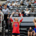 randall-showcase-2026-jpegJoe-pps-32 | Press Pass Sports Liberty player #12 in red uniform raises hands to set the volleyball during a rally, with a referee and audience in the background.