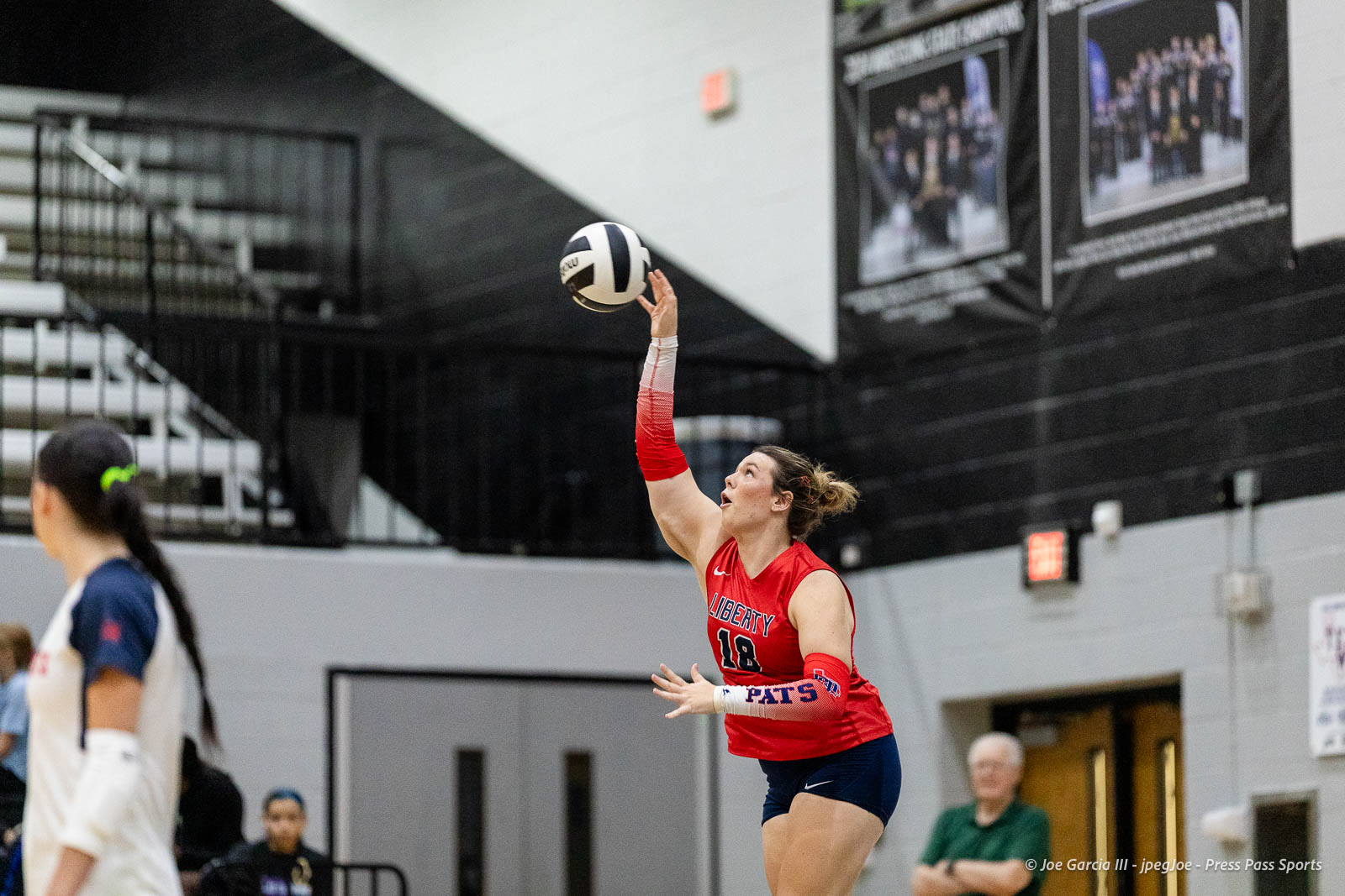 randall-showcase-2026-jpegJoe-pps-40 | Press Pass Sports Female volleyball player in a red jersey (number 18) jumps to hit a ball in a gym.