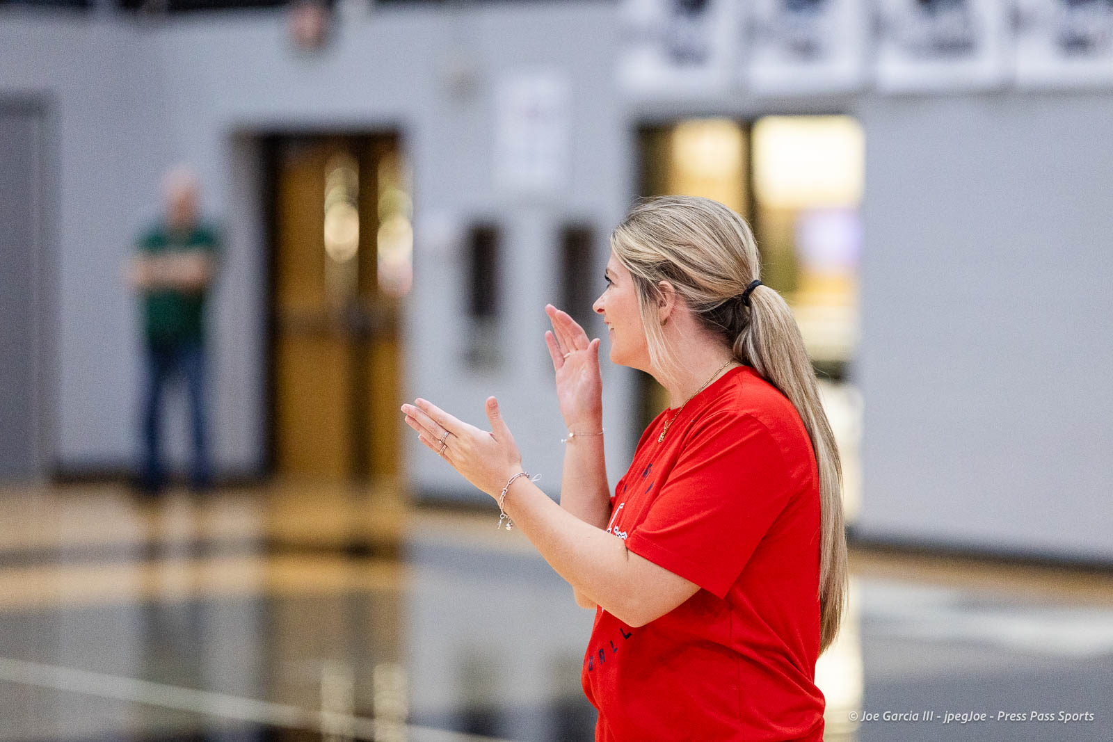 randall-showcase-2026-jpegJoe-pps-52 | Press Pass Sports Side profile of a blonde woman in a red shirt, gesturing with her hands while speaking in a gym.