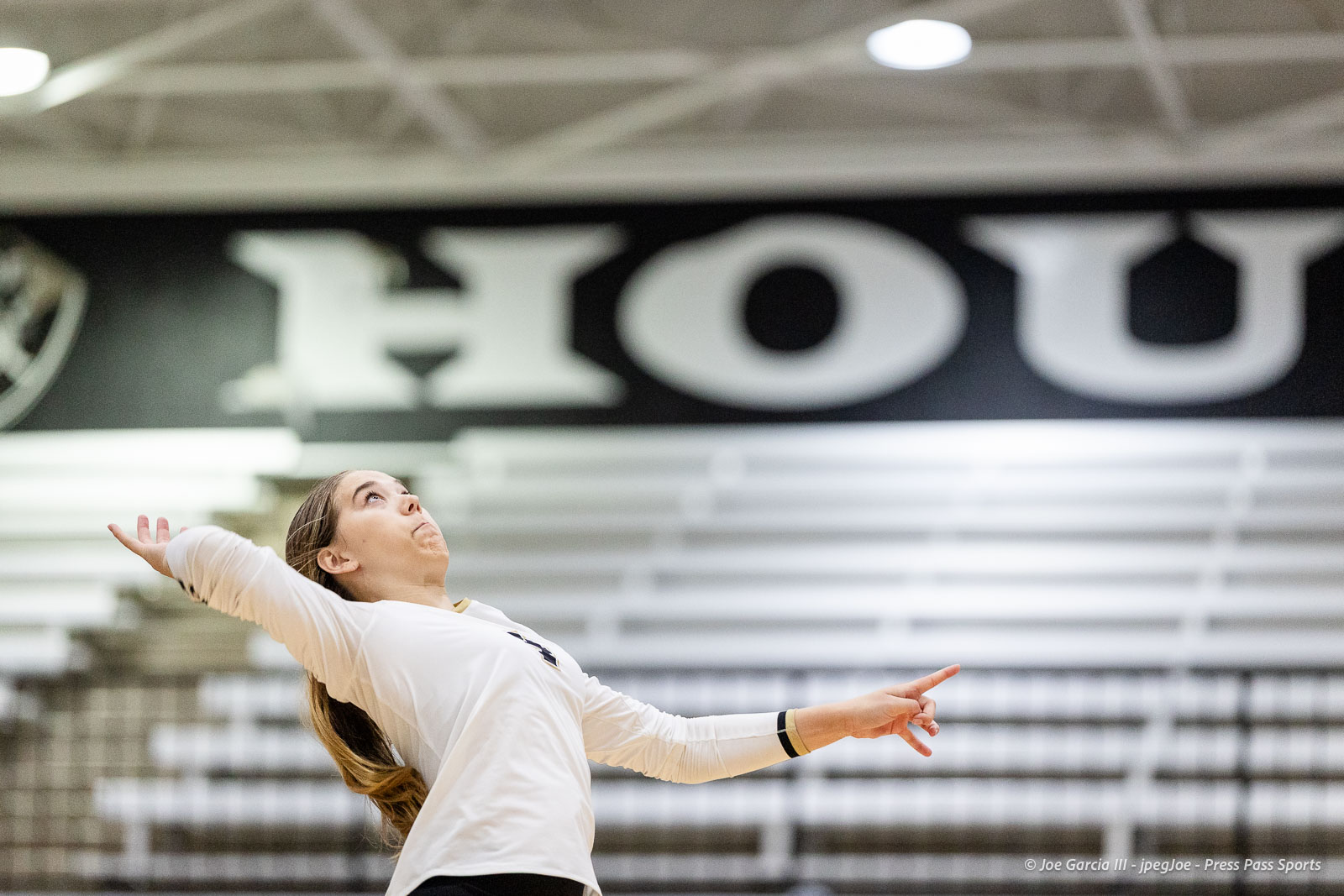 randall-showcase-2026-jpegJoe-pps-55 | Press Pass Sports Woman in a white top dancing in a gym, arms extended, looking up with a large blurred sign in the background for context as a performance image.