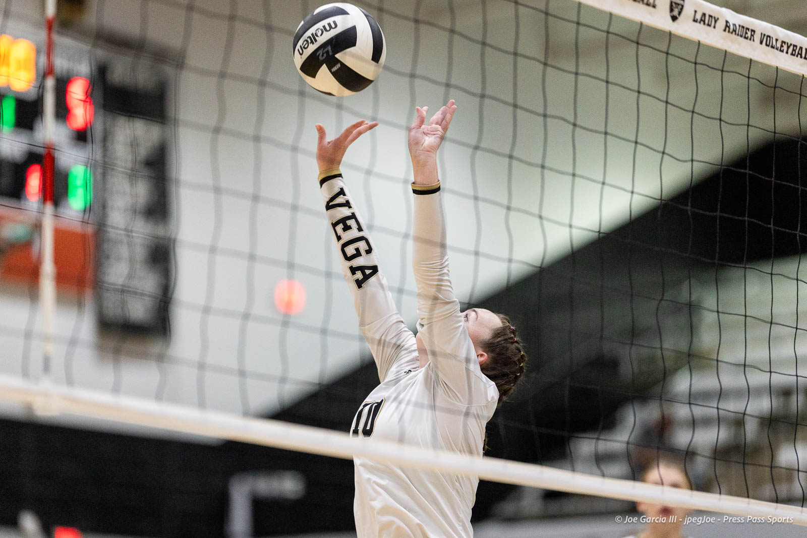 randall-showcase-2026-jpegJoe-pps-68 | Press Pass Sports Volleyball player in a white jersey reaches up to block the ball at the net in an indoor gym.