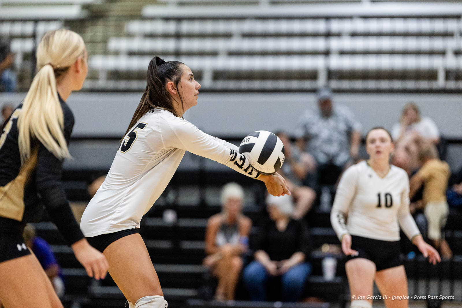 randall-showcase-2026-jpegJoe-pps-80 | Press Pass Sports Female volleyball player in a white jersey (#5) passing the ball on a gym court, with teammates and blurred spectators in the background.