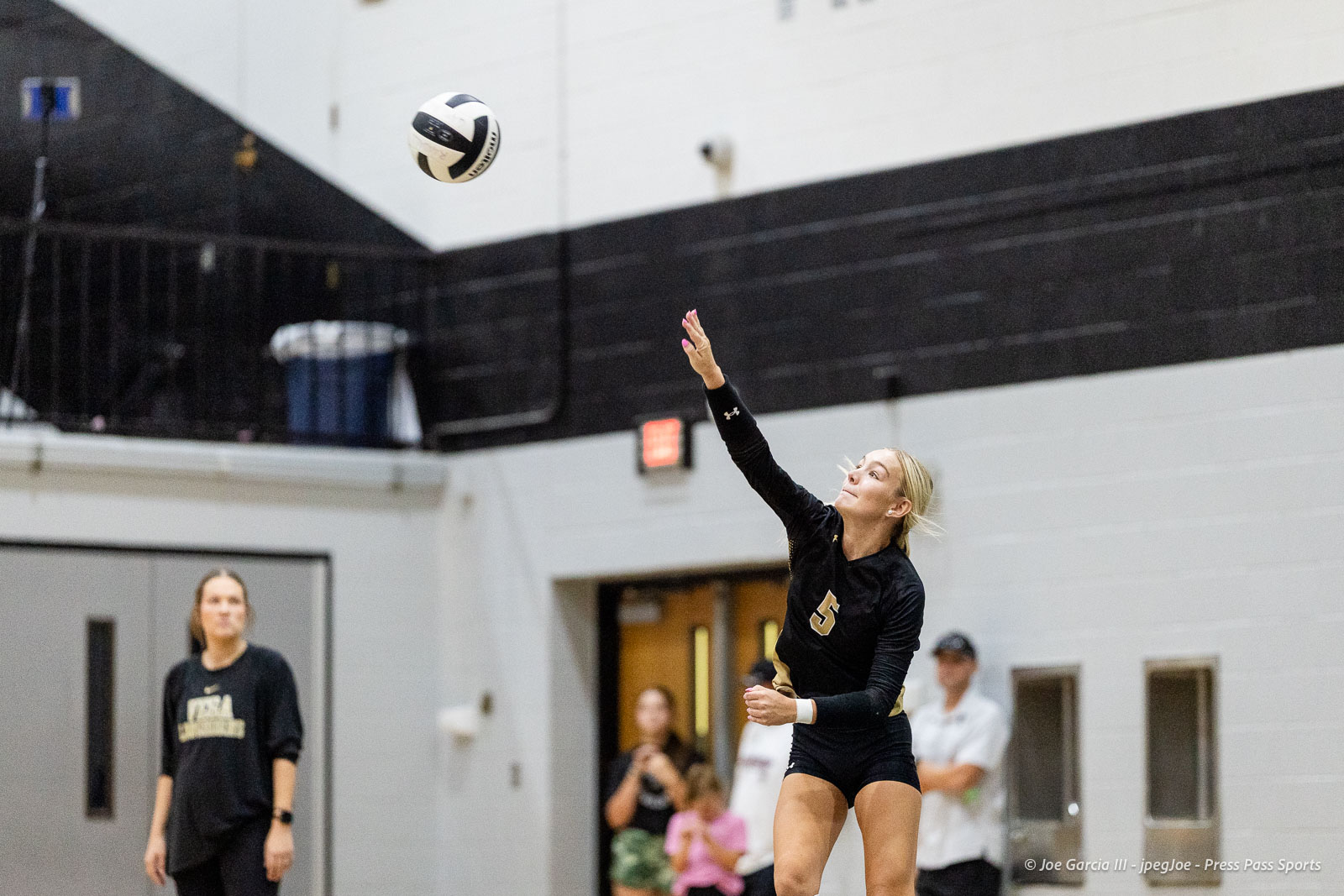 randall-showcase-2026-jpegJoe-pps-82 | Press Pass Sports Female volleyball player in black uniform (number 5) leaps to hit the ball in an indoor gym as onlookers watch in the background.