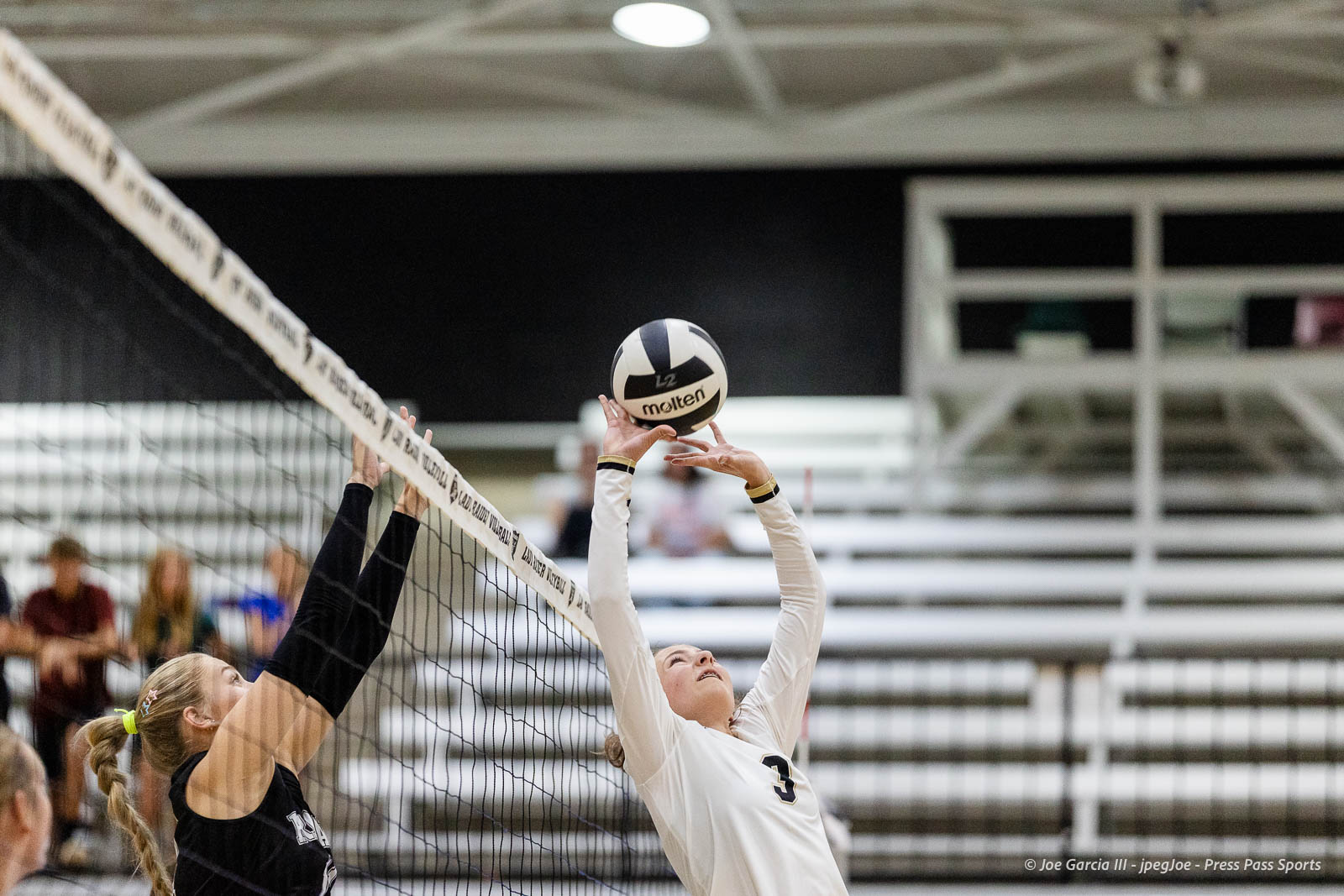 randall-showcase-2026-jpegJoe-pps-86 | Press Pass Sports Two female volleyball players reach for the ball at the net during an indoor match.