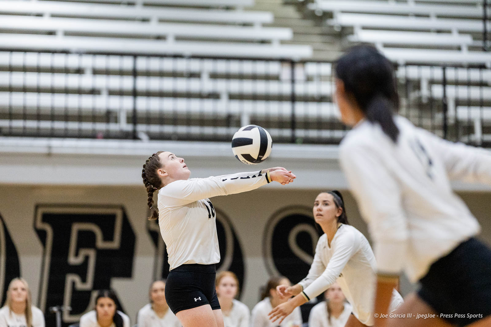 randall-showcase-2026-jpegJoe-pps-89 | Press Pass Sports A female volleyball player in a white jersey bumps the ball while others watch in a gym.