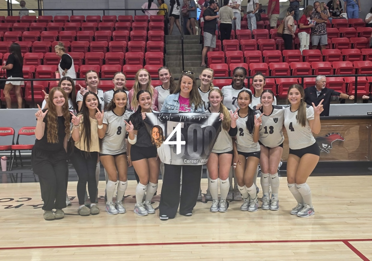 IMG_1750 | Press Pass Sports Girls' volleyball team posing for a milestone photo with a banner that reads '400 Career Wins' in a gym with red bleachers behind them.