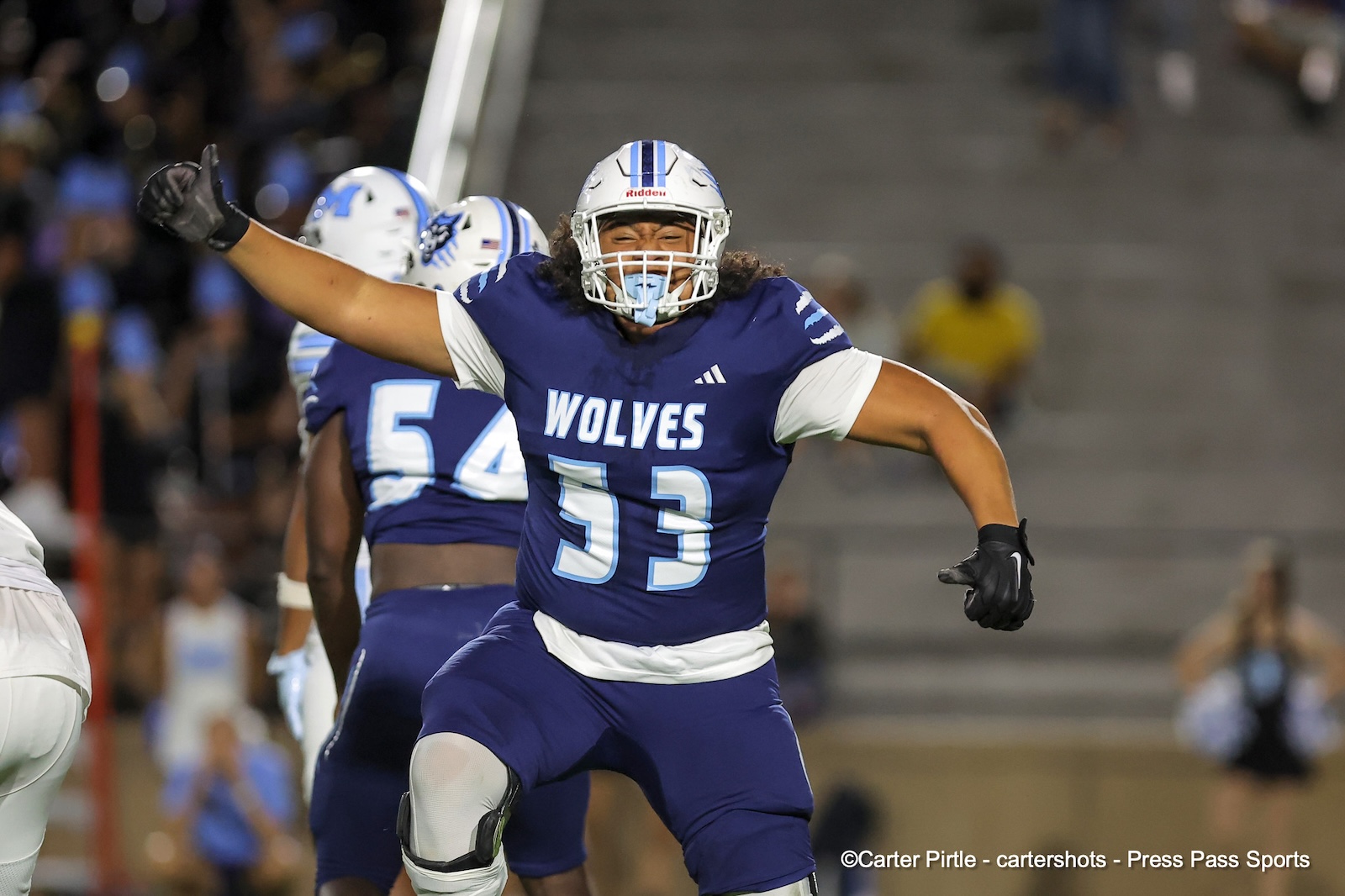 Football player in a blue Wolves jersey (#93) celebrating with arms outstretched on the field, helmet on.