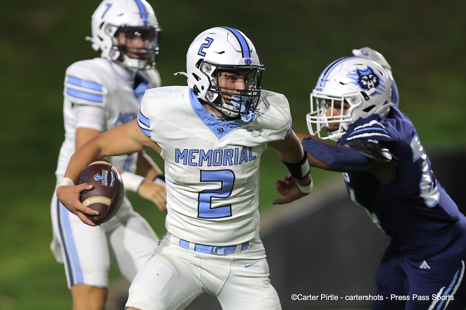 Football player in a white Memorial jersey #2 carries the ball while a defender closes in from the right.