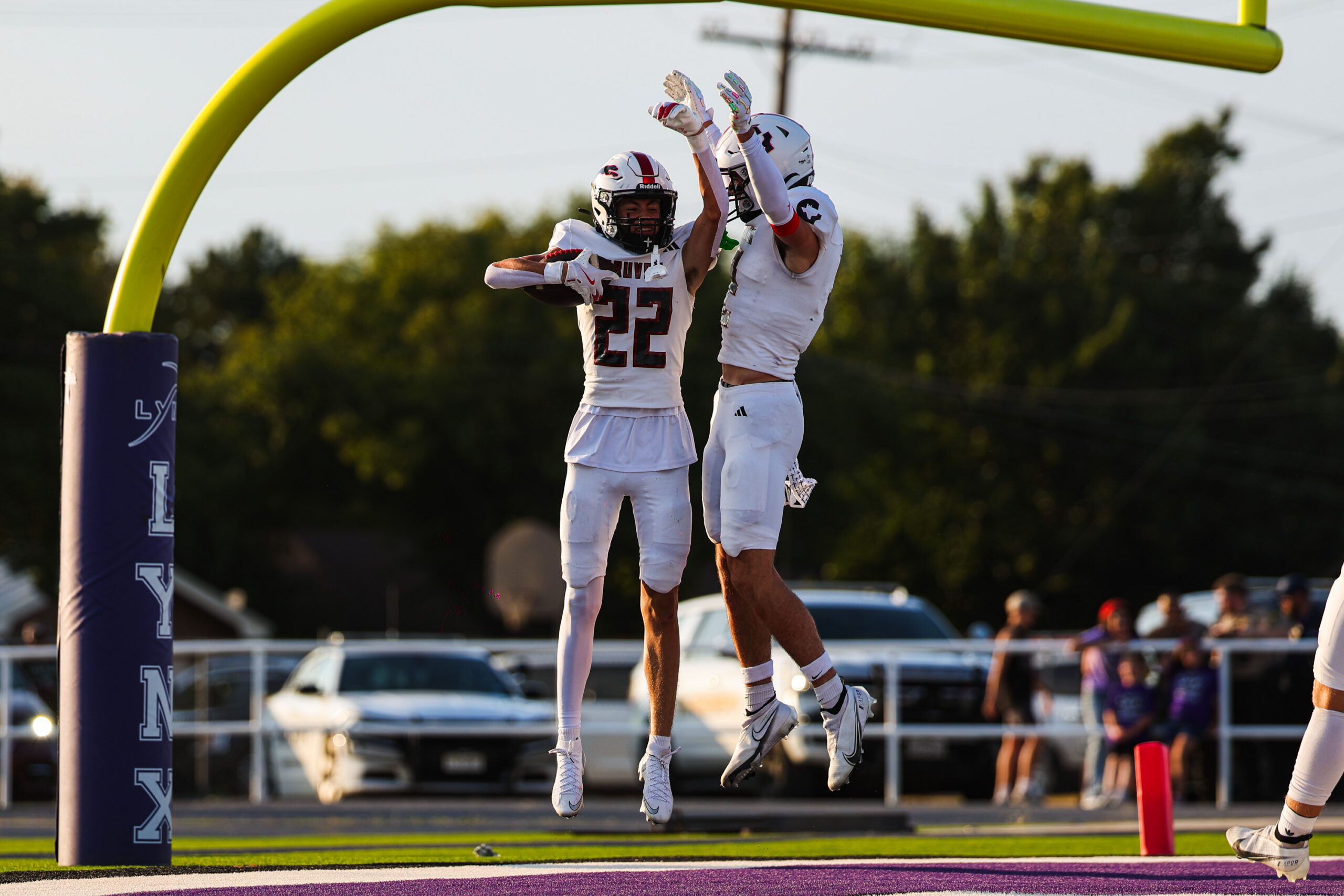 MAIRYN-03 | Press Pass Sports Two football players in white uniforms jump in celebration in the end zone under a yellow goalpost pad.