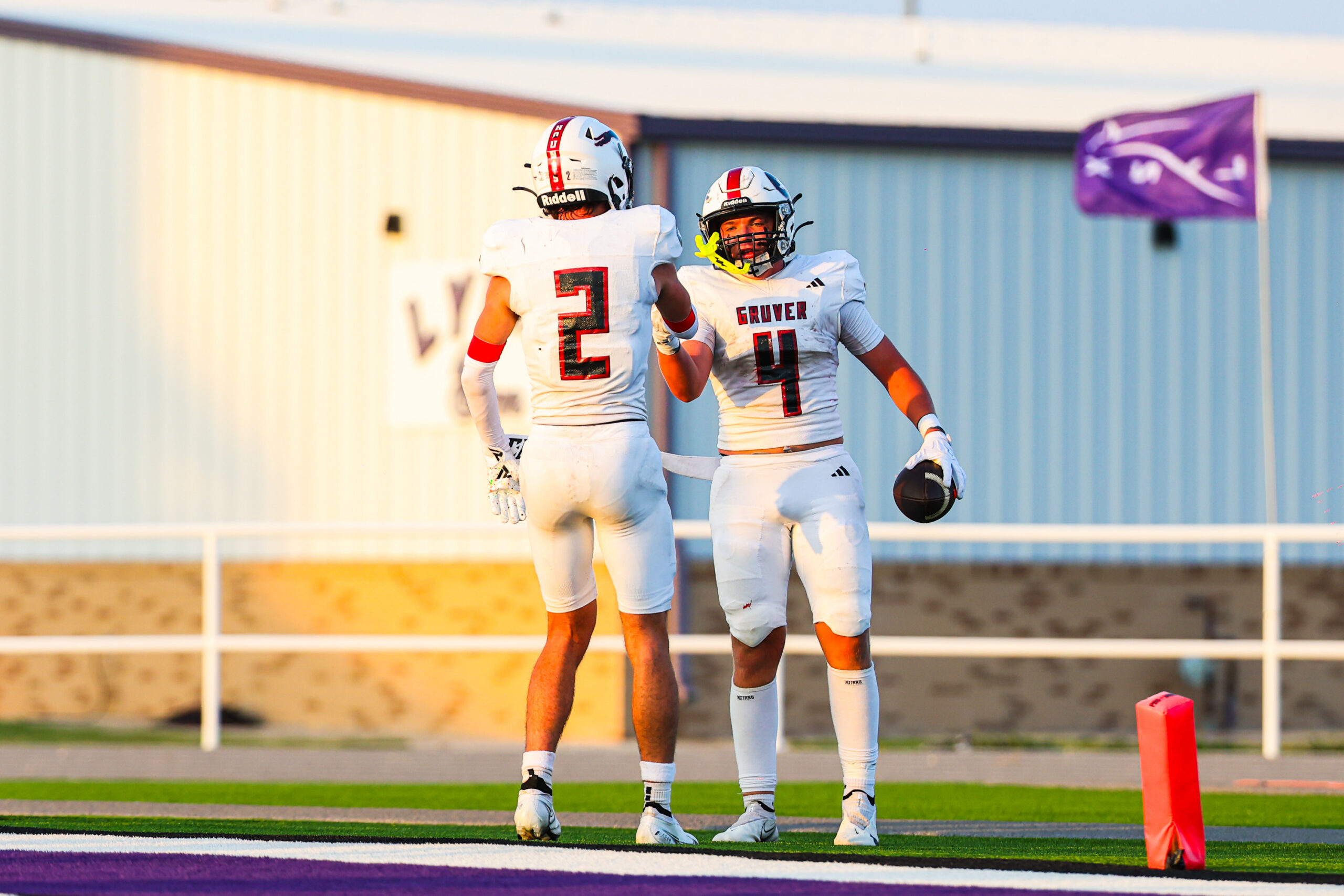 MAIRYN-08 | Press Pass Sports Two football players in white uniforms celebrate on the sideline, numbers 2 and 4, with a purple flag in the background.