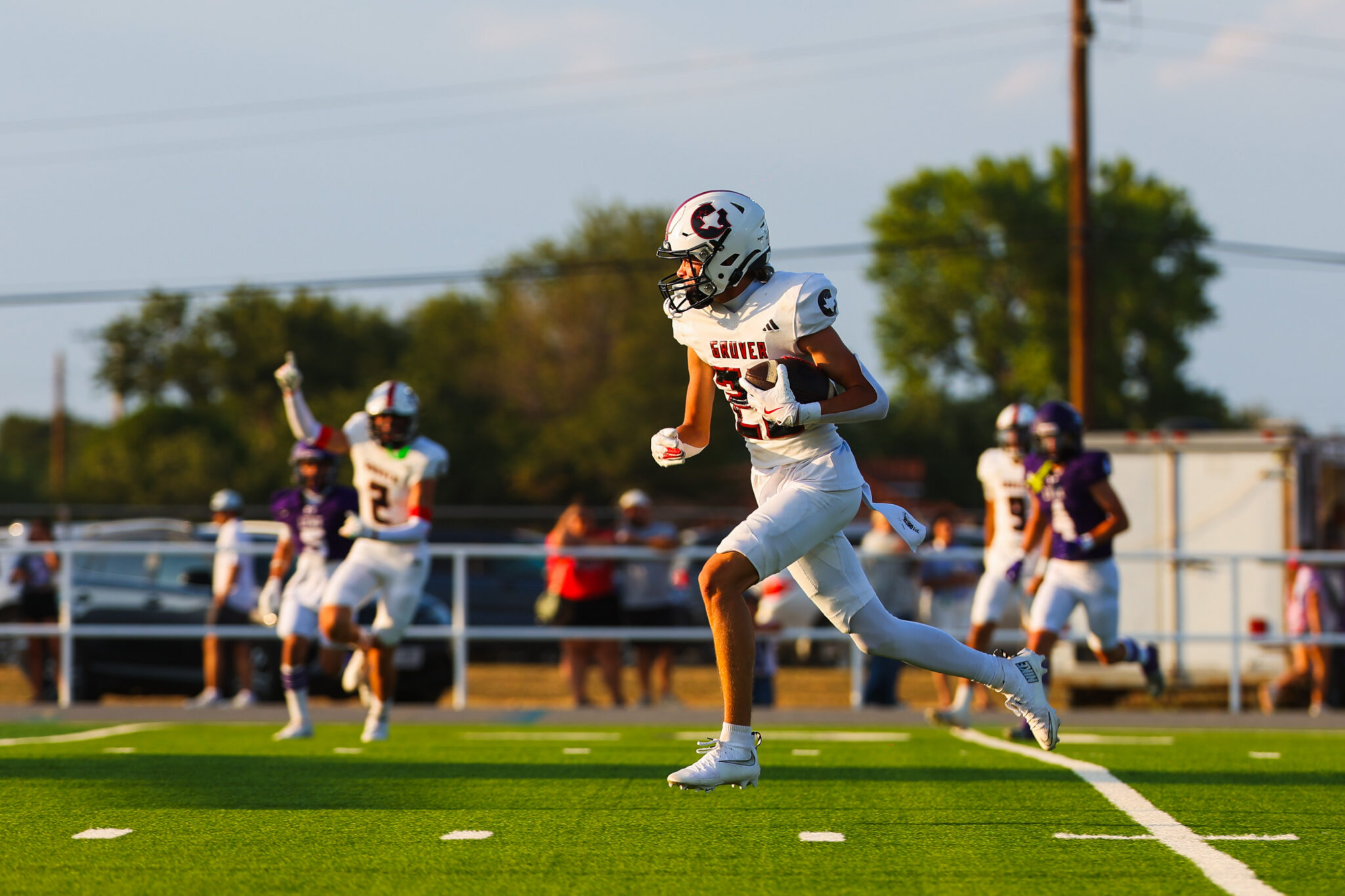 MAIRYN-18 | Press Pass Sports Football player in a white uniform carrying a football and sprinting down the field during a game on a green turf.