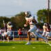 MAIRYN-18 | Press Pass Sports Football player in a white uniform carrying a football and sprinting down the field during a game on a green turf.