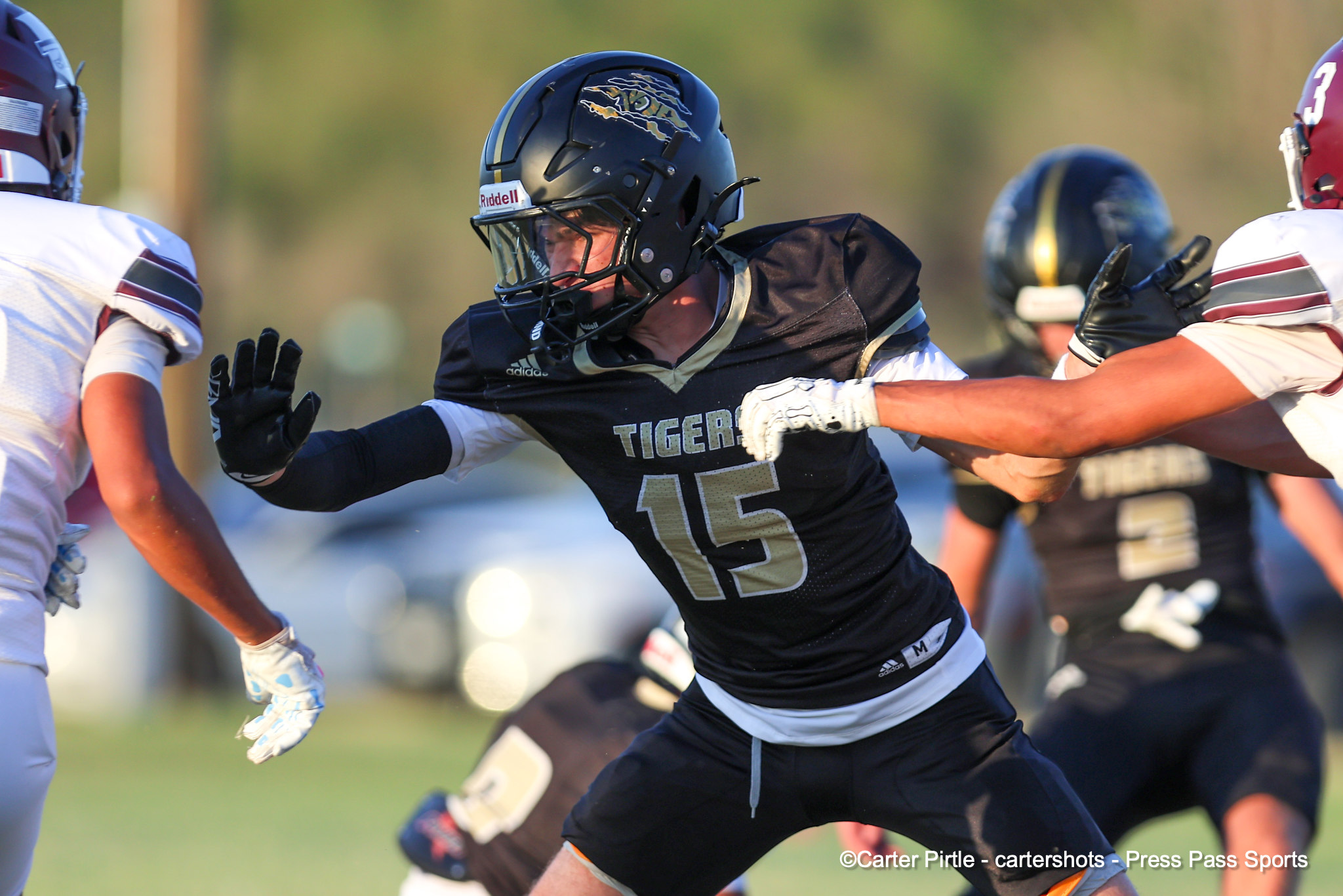 High-action moment in a football game: a black-uniformed player with number 15 runs forward while teammates and opponents converge around him.