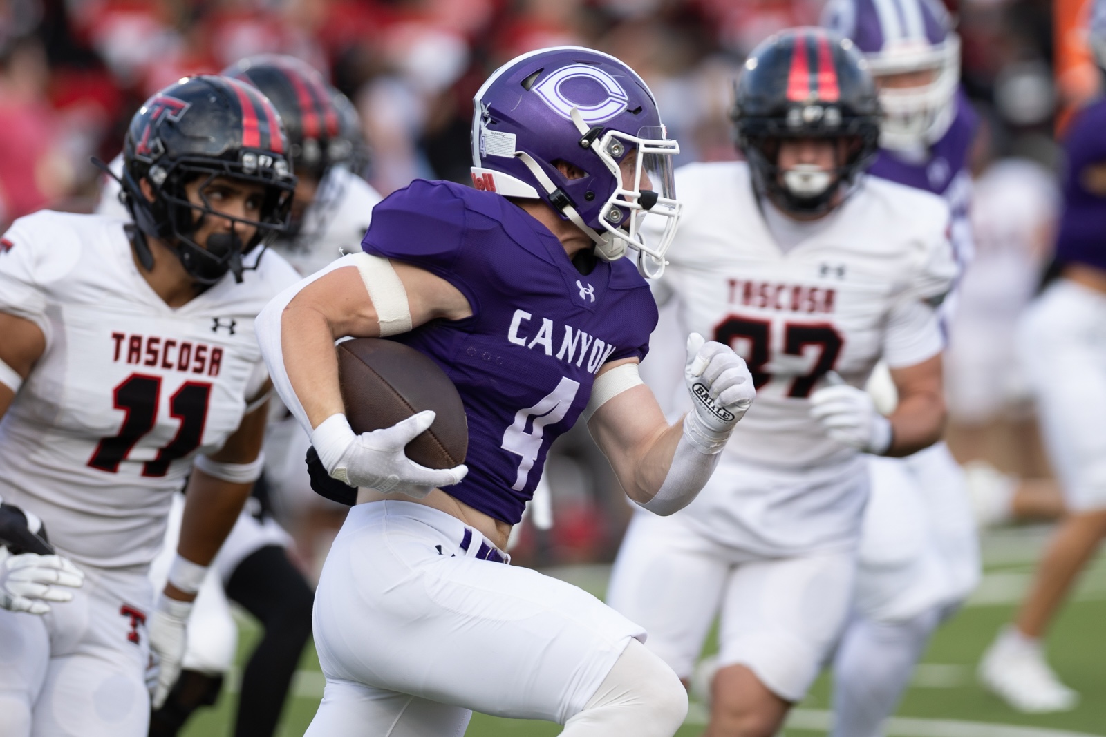 THS-CHS-FB-5 | Press Pass Sports Canyon player in a purple jersey (#4) runs with the football as Tascosa defenders in white chase him.