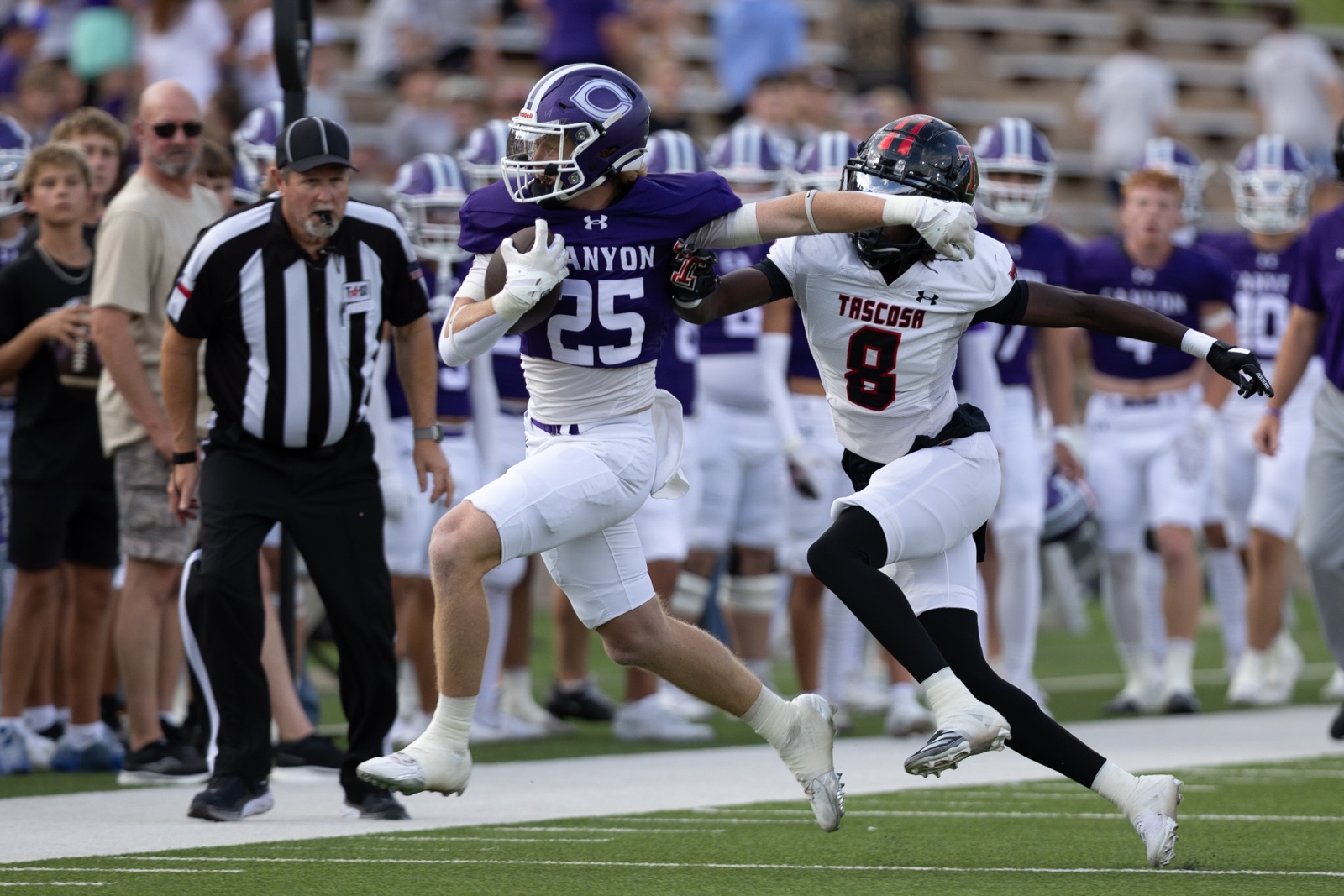 THS-CHS-FB-7 | Press Pass Sports Purple team ball carrier (#25) runs along the sideline as a Tasosa defender (#8) reaches to tackle him.