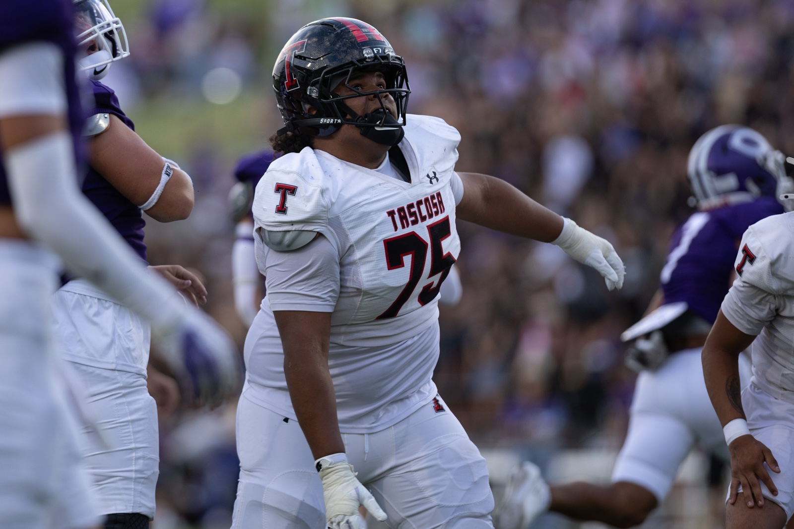 THS-CHS-FB-17 | Press Pass Sports Tascosa football player in white jersey number 75 charges forward on the field during a game under a blurred crowd backdrop.