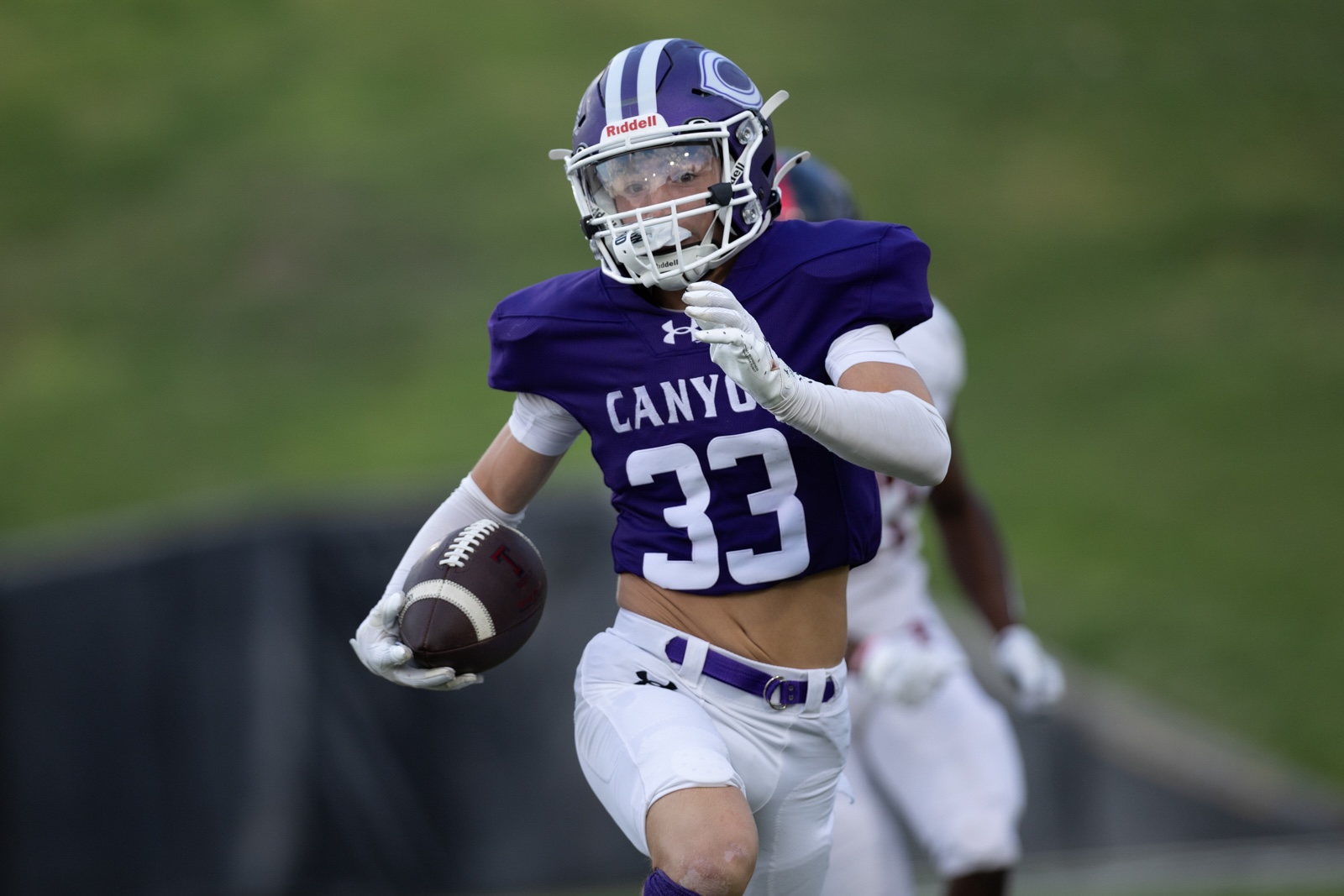 THS-CHS-FB-19 | Press Pass Sports Football player in a purple Canyon jersey (#33) runs with the ball during a game, white pants and helmet visible.