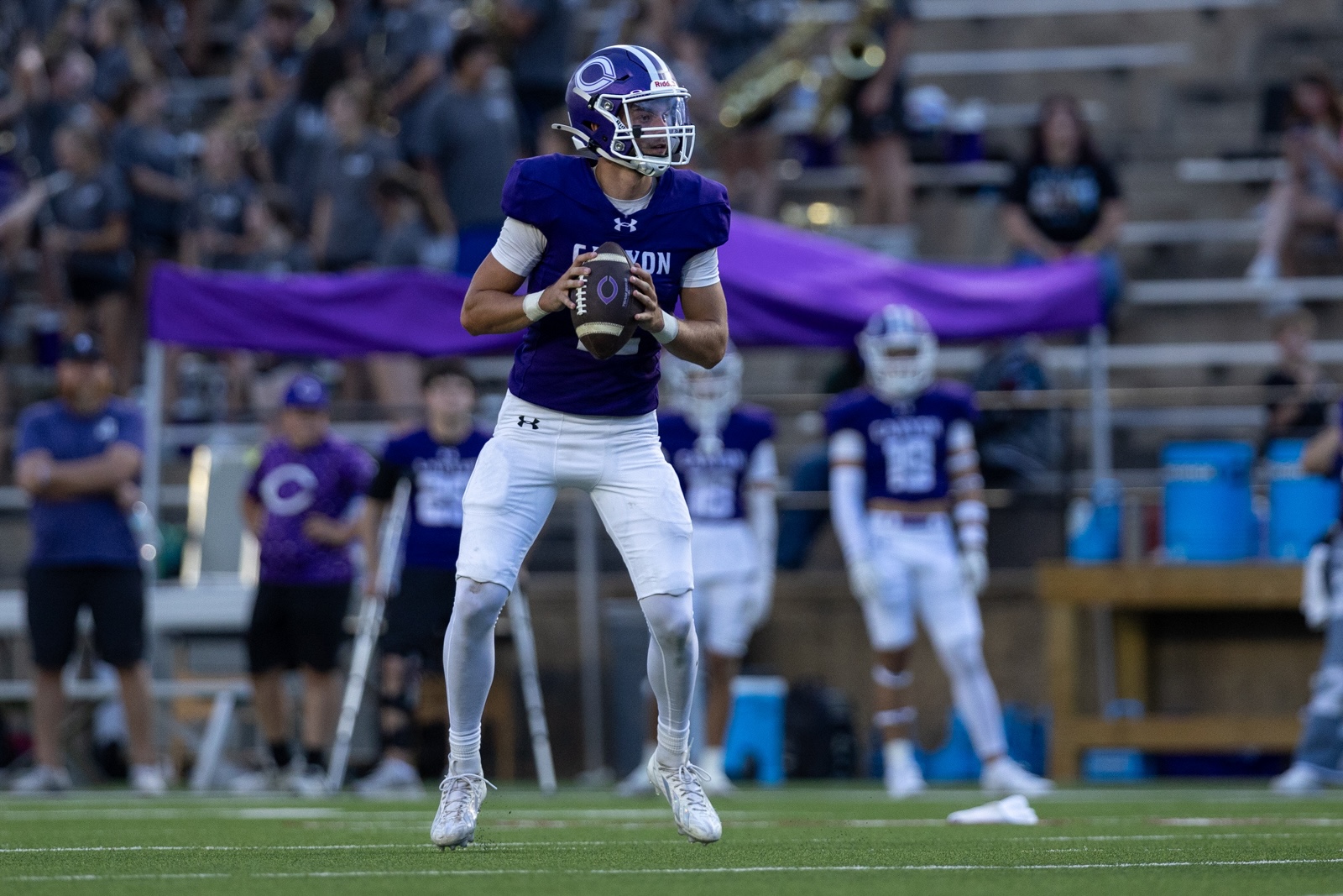 THS-CHS-FB-24 | Press Pass Sports Quarterback in a purple jersey catches a football on a green football field during a game.
