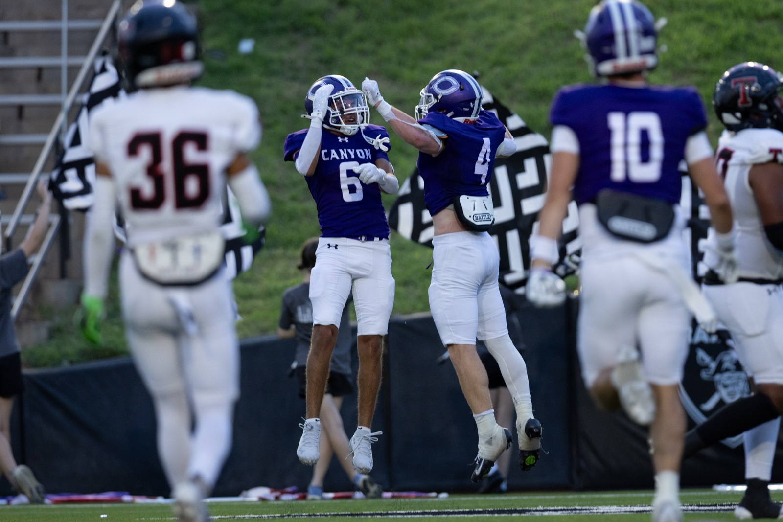 THS-CHS-FB-28 | Press Pass Sports Two football players in blue Canyon jerseys leap and high-five in celebration on the field.