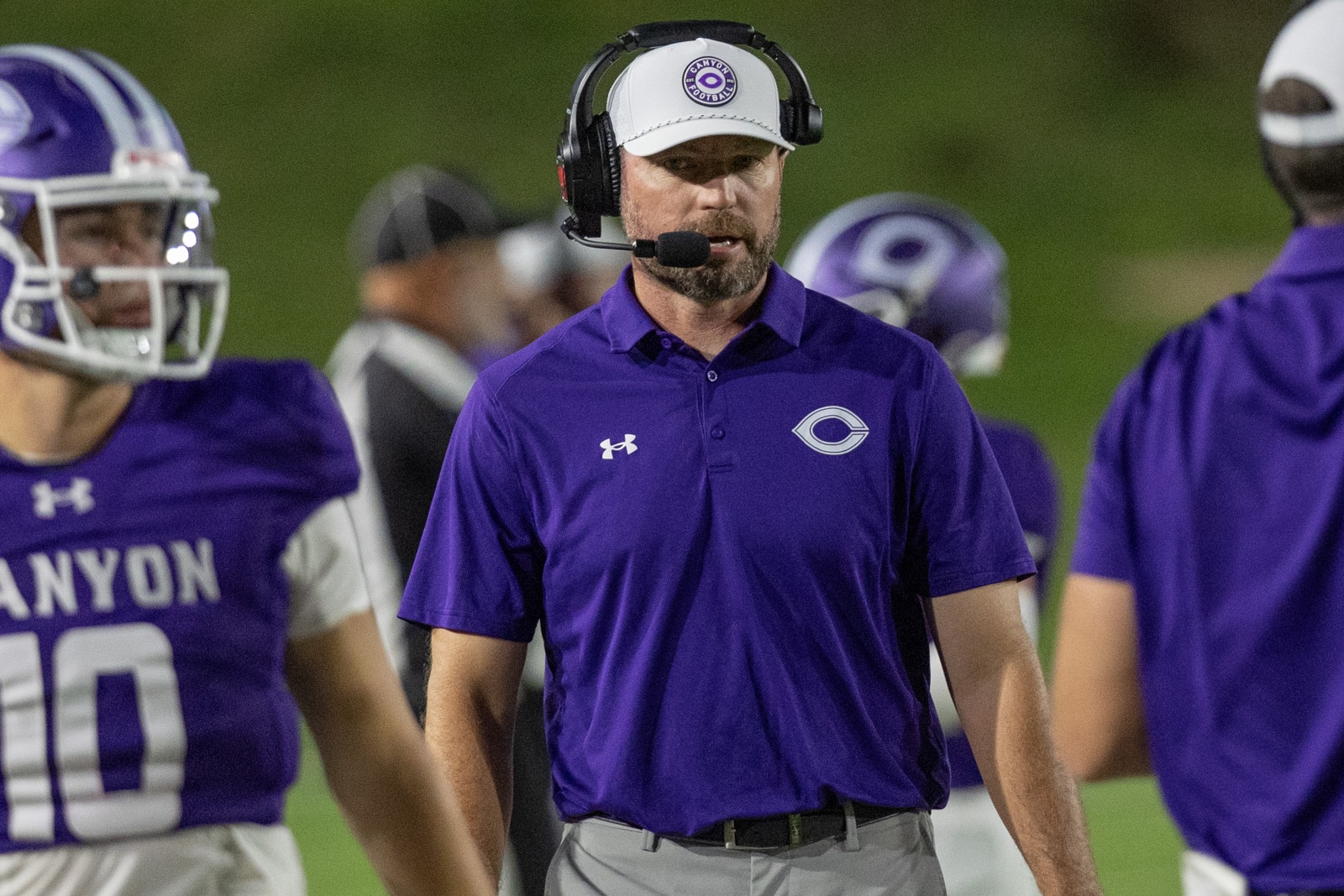 THS-CHS-FB-37 | Press Pass Sports Football coach wearing a purple polo with a C logo and headset on the sideline.