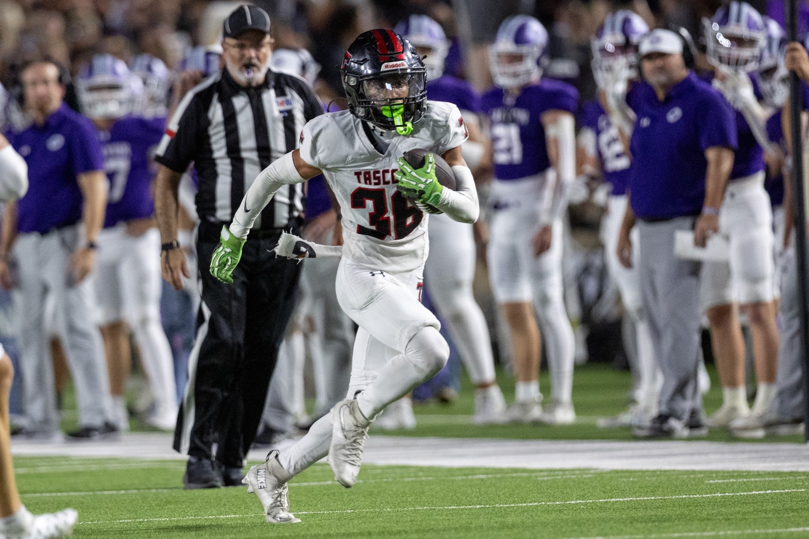 THS-CHS-FB-38 | Press Pass Sports Football player wearing white uniform #35 runs with the ball on a green field, neon green gloves and mouthguard visible, sideline in background with referees and purple-uniform players