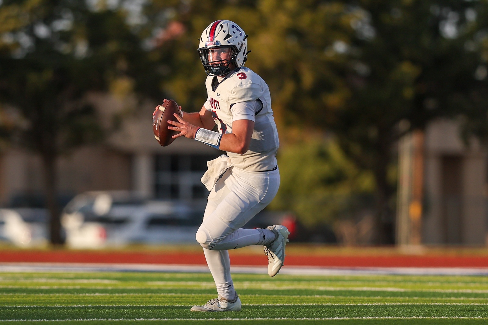 Seabolt Chase-16843 | Press Pass Sports Football player in white uniform runs with the ball on a green turf field during a game, preparing to dodge.