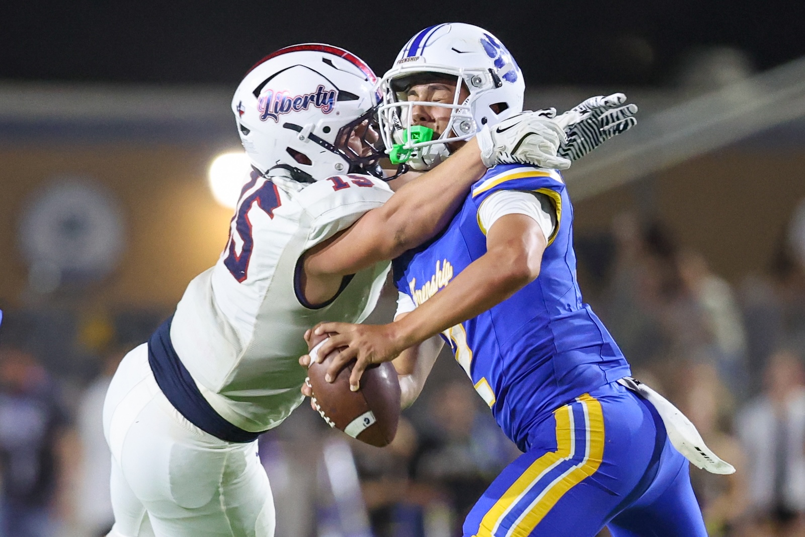 Seabolt Chase-18033 | Press Pass Sports Two football players in white and blue collide as the defender attempts to tackle the ball carrier, holding the ball tight